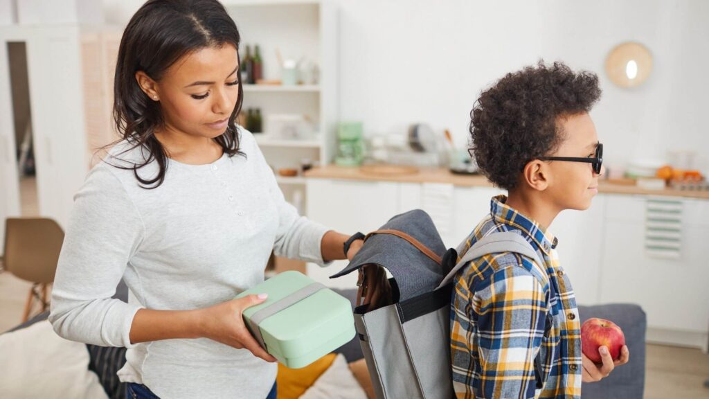 Mom Putting Lunch In Son's Backpack