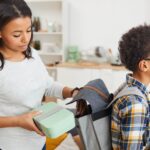 Mom Putting Lunch In Son's Backpack