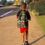 Young Boy Walking Down Sidewalk To School